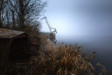 Rusty old industrial dock cranes at swampland