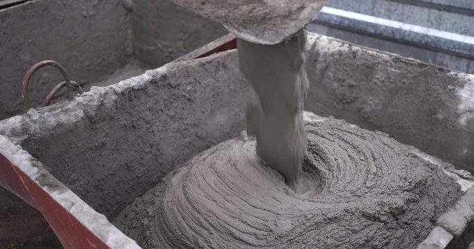 Close-up of a mortar pouring through a spout, a large flow from a concrete mixer