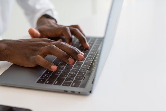 Close up of african business man hands working using keyboard of computer laptop