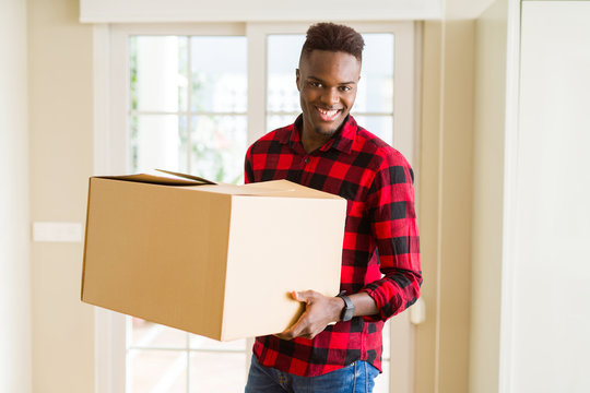 Young african american man holding a carton box, packing cardboard delivery package at home