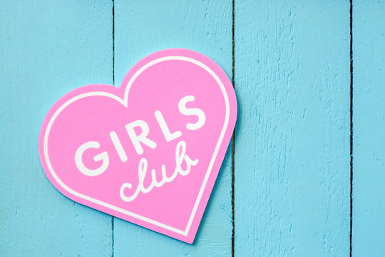 .pink heart-shaped girl club sign on a blue fence background. concept of fashion promotion