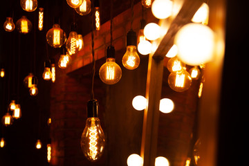 classic different retro light bulbs hanging on brick wall background at night