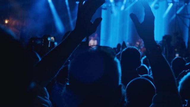 Silhouette hands of audience crowd people use smart phones enjoying the concert. Big crowd at concert cheering clapping hands at night rock concert. 4k, UHD