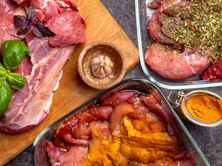 Raw meat background. with a variety of herbs and spices. On the grey concrete table. Close up