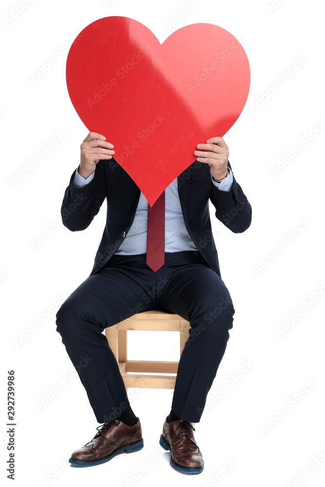 Poster happy young businessman hiding behind big red heart