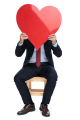 happy young businessman hiding behind big red heart