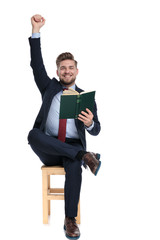 enthusiastic young businessman reading and holding arms up