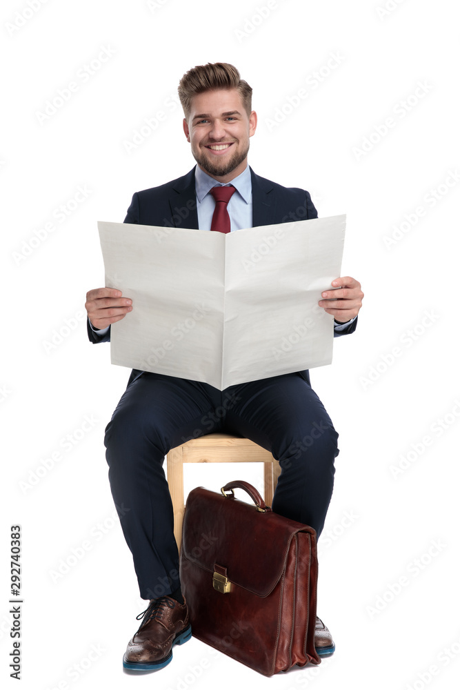 Poster happy young businessman holding newspaper in studio