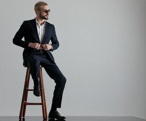 businessman sitting and holding his jacket's button looking sideways