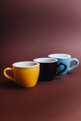 Threee colorfull cups of espresso coffee on dark background