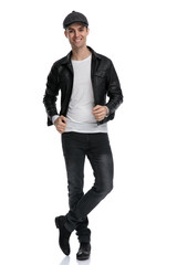 casual man standing with crossed legs fixing jacket happy