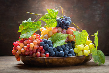 mix of fresh ripe grapes with leaves in a bowl