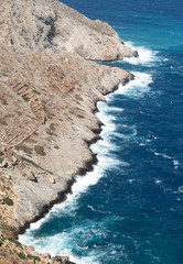 Greece, the island of Folegandros. Sheer cliffs seen from the islands capital the Hora.  Waves and sea spray on a windy day.