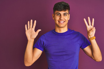 Young indian man wearing t-shirt standing over isolated purple background showing and pointing up with fingers number eight while smiling confident and happy.