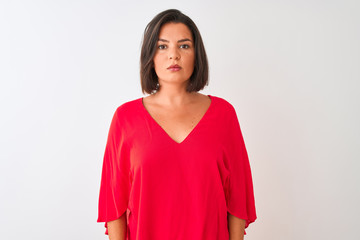 Fototapeta premium Young beautiful woman wearing red t-shirt standing over isolated white background with serious expression on face. Simple and natural looking at the camera.