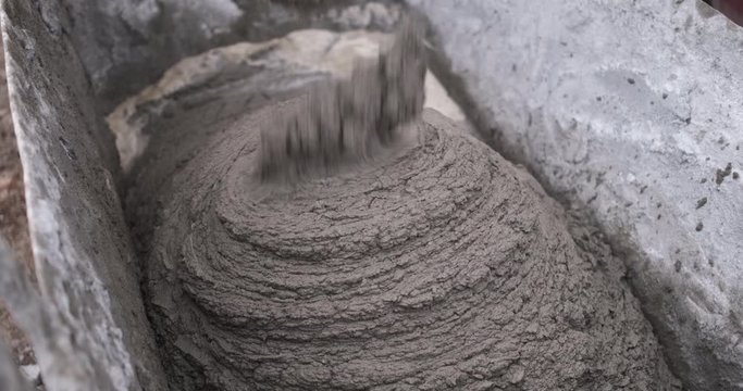 Close-up of a mortar pouring through a spout, a large flow from a concrete mixer