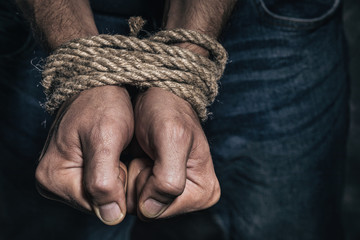 Mens hands tied with a rope, close-up. Concept of imprisonment in modern society