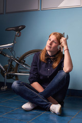 Plakat pretty girl sitting on the floor of a bike shop near a bike