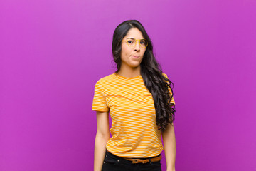 young pretty latin woman feeling confused and doubtful, wondering or trying to choose or make a...