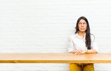 young  pretty latin woman looking worried, stressed, anxious and scared, panicking and clenching...