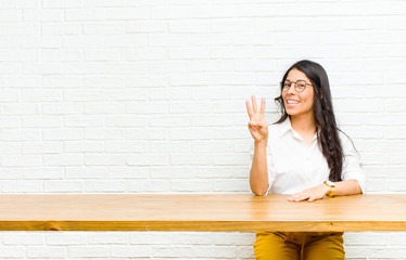 young  pretty latin woman smiling and looking friendly, showing number three or third with hand...
