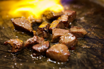cooking beef steak on fire flaming barbecue in hot black pan