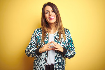 Young beautiful woman wearing casual jacket over yellow isolated background Hands together and fingers crossed smiling relaxed and cheerful. Success and optimistic