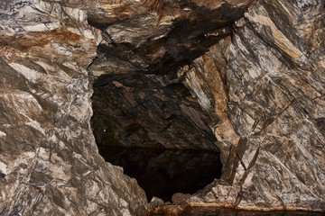 Cave in marble rock.A cave in a former underground marble quarry. Brown natural marble and its texture are visible. Russia, Karelia, Ruskeala mountain park.