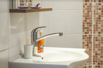 Close-up of the white sink in bathroom.  Liquid soap. Filtered.