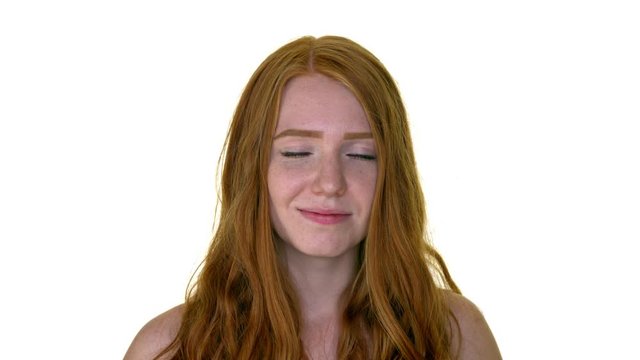 Attractive young redhead woman framing her eyes with her hands
