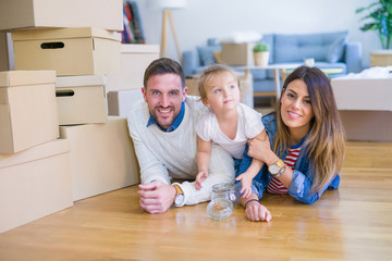 Beautiful famiily with kid lying down at new home around cardboard boxes