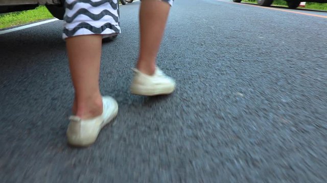 a small child walks along on road, shoot at foot step.