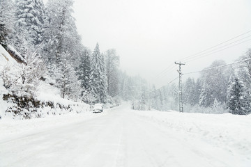 Snowy road in winter with an SUV parked.