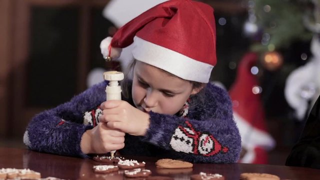 Little girl with santa hat is drawing Christmas gingerbread