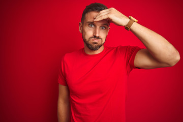 Fototapeta na wymiar Young handsome man wearing casual t-shirt over red isolated background worried and stressed about a problem with hand on forehead, nervous and anxious for crisis