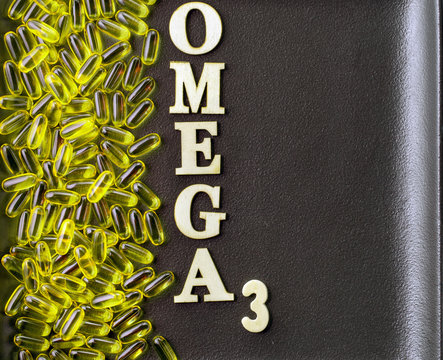 Omega-3 pills from left side of dark background with text and copy space, top view