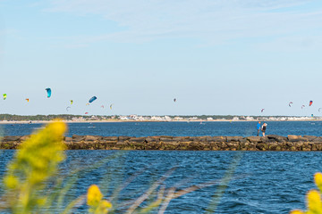 Couple Walkkng on the Jetty at Bass River with Late September Surfers at West Dennis Beach, Cape Cod, Massachusetts on a Beautiful Clear and Sunny Day