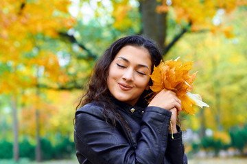 woman posing with autumn leaves in city park, outdoor portrait