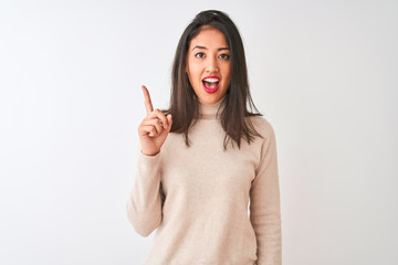 Beautiful chinese woman wearing turtleneck sweater standing over isolated white background pointing finger up with successful idea. Exited and happy. Number one.