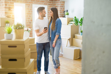 Young couple moving to a new house, using smartphone smiling very happy for new apartment