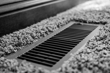 Focus on floor vent in room with carpet