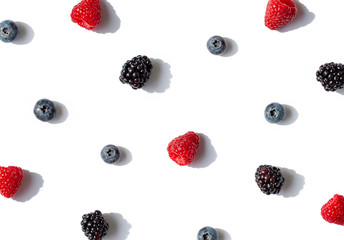 Raspberries, blueberries and blackberries seamless contrast pattern with shadows on the white background. Top view.