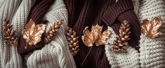 Autumn background with cozy sweaters and gold leaves .
