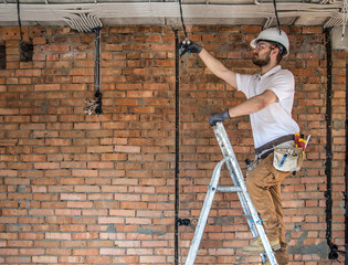 Electrician with tools, working on a construction site. Repair and handyman concept. © puhimec