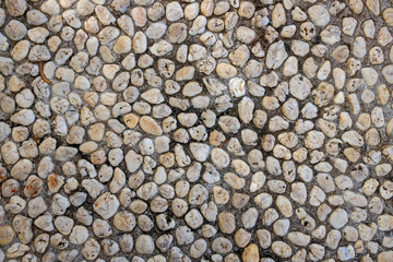 Abstract photo texture of pebble paving, top view background. White pebbles in grey sand top view. Rounded marble paving