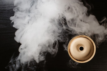  clay bowl for tobacco on a black background with smoke around