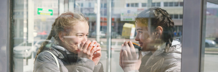 smiling young teen girlfriends drinking coffee or tea and gossiping outdoors, people, communication and friendship concept