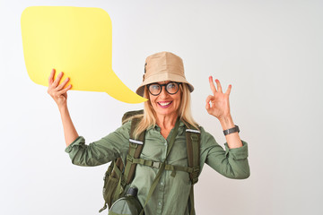 Senior hiker woman wearing canteen holding speech bubble over isolated white background doing ok sign with fingers, excellent symbol