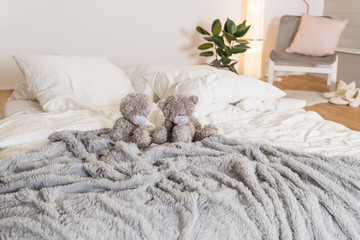 Scandinavian bedroom room with standing lamp, plant, grey wall, white furniture, teddy bears. Cute modern interior and toys.Stylish and bright scandinavian decor.Cosy bedroom with eco decor.