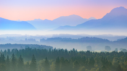 Fototapeta na wymiar Aerial panoramic landscape of Alpine foggy foothills with morning sunrise over mountains